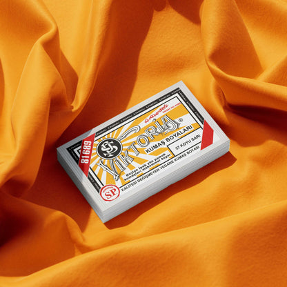 Package of egg-yolk yellow fabric dye on vibrant orange fabric background