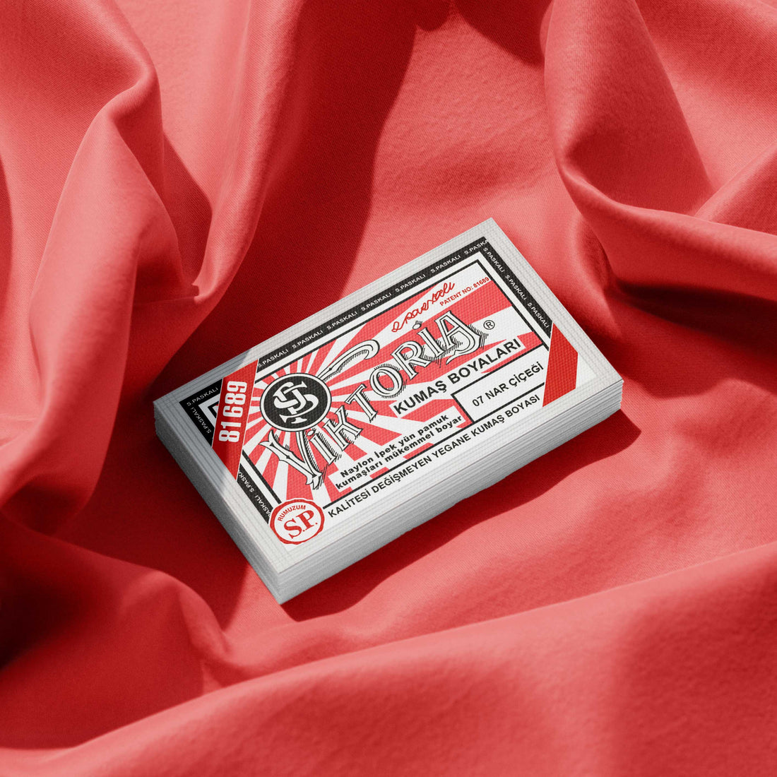 Pack of salmon red fabric dye placed on a vibrant red fabric background